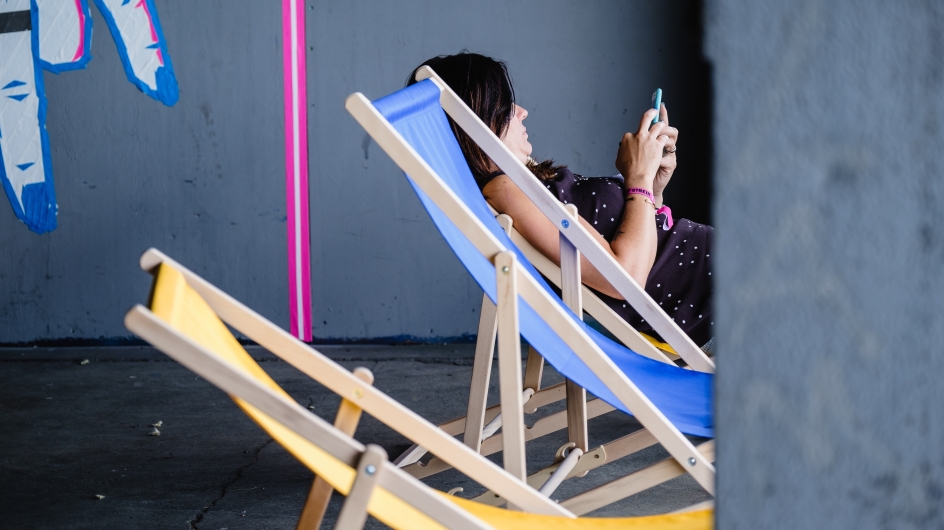 Get-together im bUm Berlin-Kreuzberg Frag im Liegestuhl mit Handy in der Hand