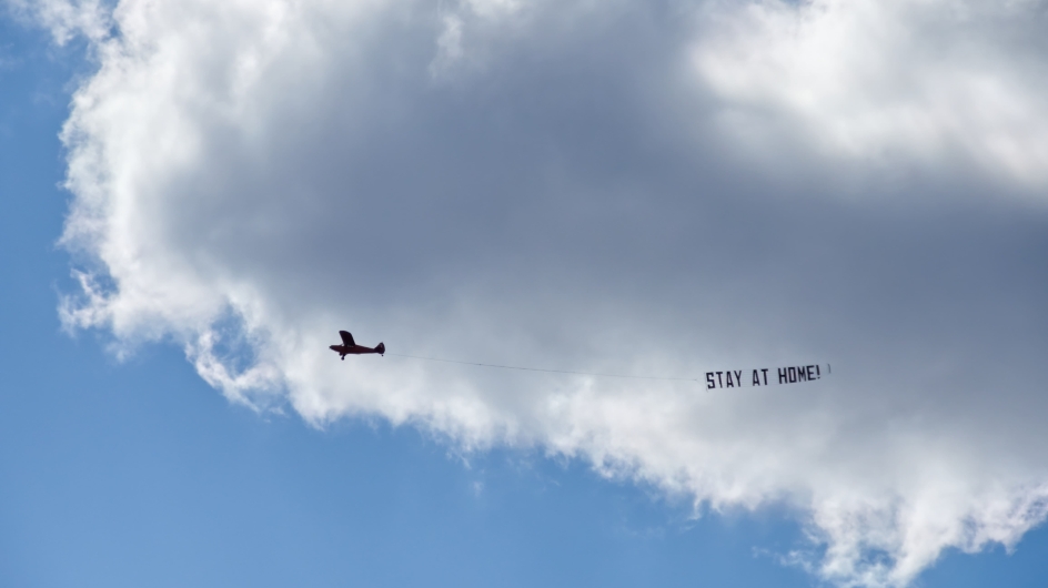 Flugzeug mit Schild "Stay at Home"