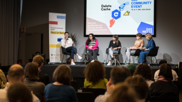 Speaker*innen des Panels sitzen auf dem Podium und diskutieren.