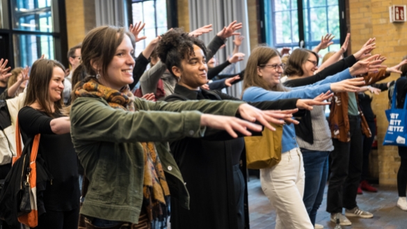 Teilnehmer*innen strecken beim Warm-Up für das Community Event 2023 die Hände nach vorne aus